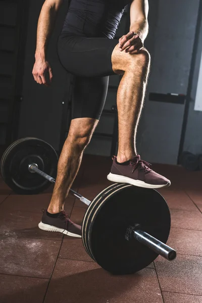 Обрезанный образ отдыхающего спортсмена, стоящего на штанге в спортзале — стоковое фото