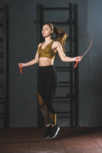 Young sportswoman doing jump rope workout  in gym — Stock Photo