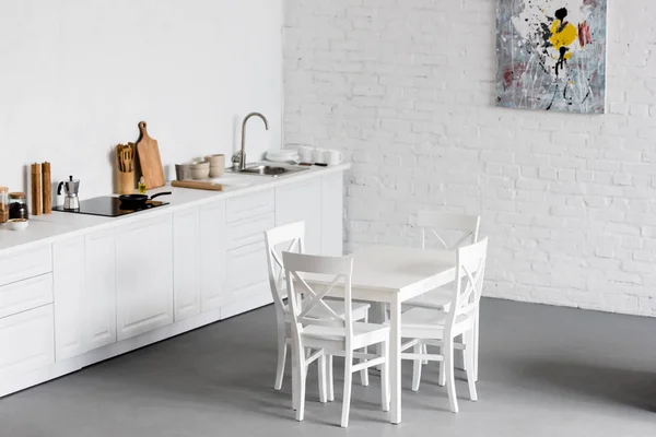Mesa de comedor blanca en la cocina moderna con paredes de ladrillo blanco - foto de stock