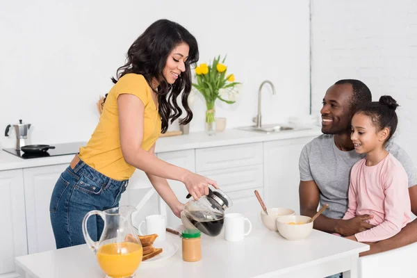 Donna versando caffè in tazze per marito e figlia — Foto stock