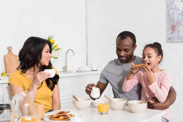 Glückliche junge Familie beim gemeinsamen gesunden Frühstück in der Küche — Stockfoto