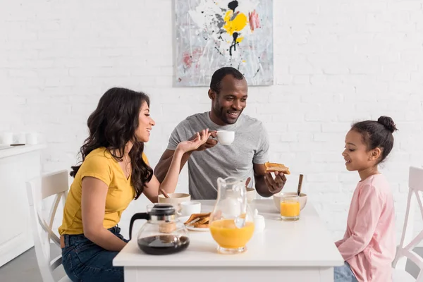 Hermosa familia joven desayunando en la cocina juntos - foto de stock