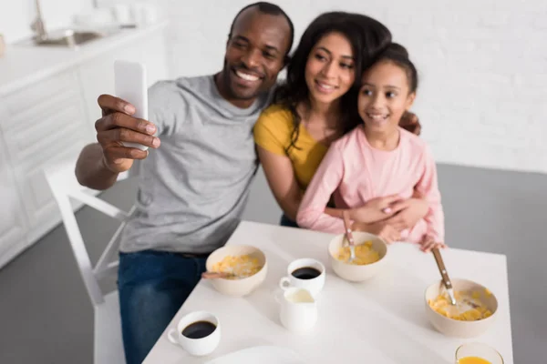 Lächelnde junge Familie macht Selfie in der Küche beim Frühstück — Stockfoto