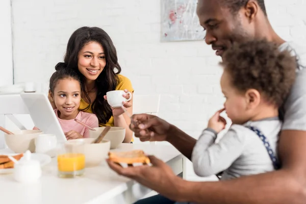 Father applying peanut butter on toast for son at kitchen — Stock Photo