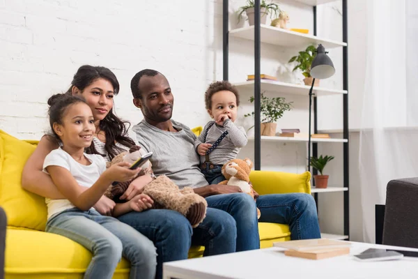 Giovane famiglia guardando la tv insieme in soggiorno — Foto stock