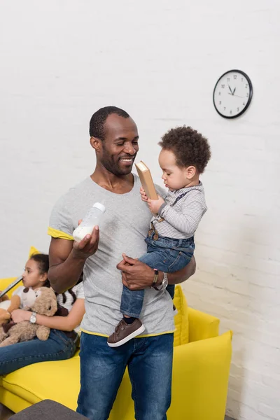 Happy young father holding son and bottle of milk — Stock Photo