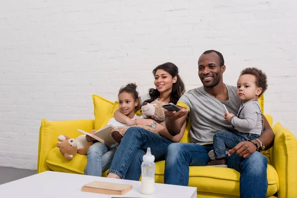 Счастливая молодая семья смотрит телевизор вместе на диване — стоковое фото