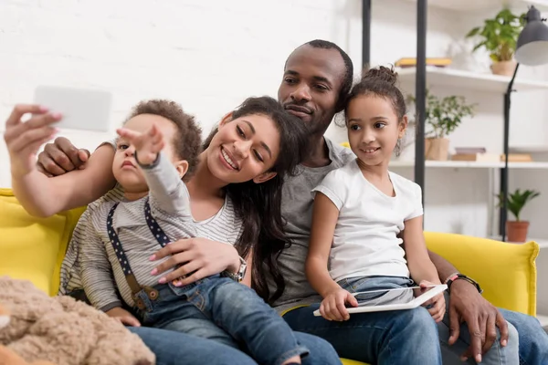 Счастливая молодая семья делает селфи на диване в гостиной — стоковое фото