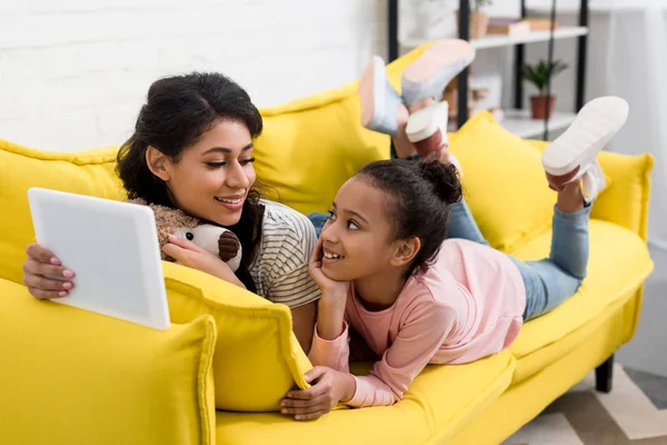 Мать и дочь используют планшет вместе на диване — стоковое фото