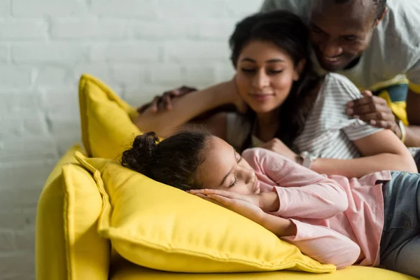 Happy parents watching on their daughter sleeping on couch — Stock Photo