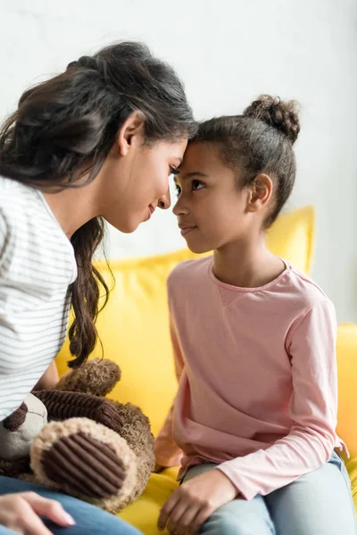 Mother and daughter looking at each other and touching with foreheads at home — Stock Photo