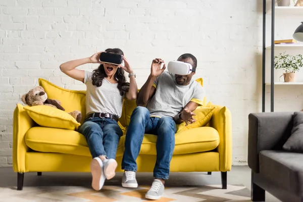 Asustada pareja afroamericana en realidad virtual auriculares sentados en el sofá - foto de stock