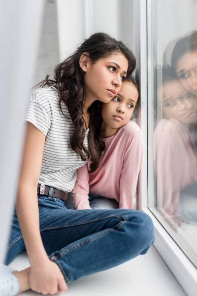 Triste mãe e filha olhando através da janela — Fotografia de Stock