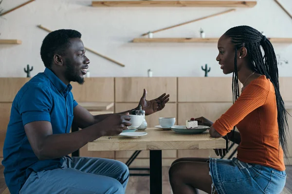 Vue latérale du couple afro-américain ayant une conversation pendant la date dans un café — Photo de stock