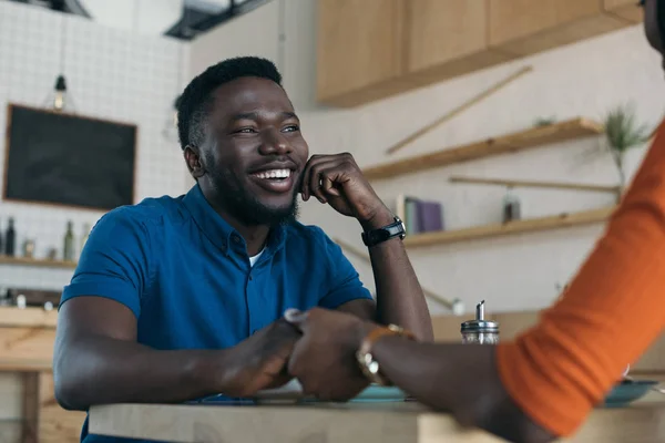 Abgeschnittene Aufnahme eines afrikanisch-amerikanischen Paares, das Händchen hält, während es am Tisch im Café sitzt — Stockfoto