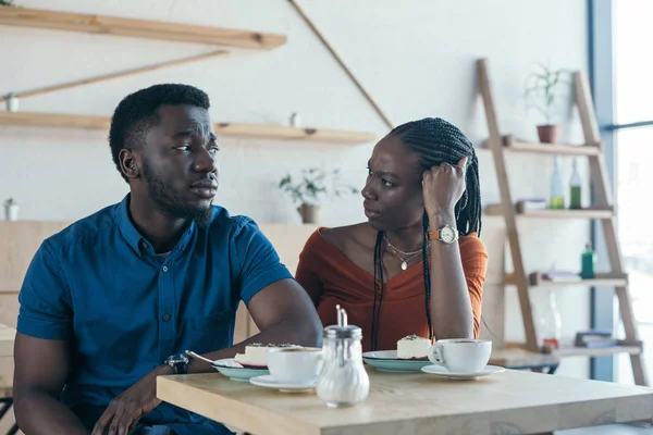 Insultado afro-americano homem sentado à mesa com namorada no café — Fotografia de Stock