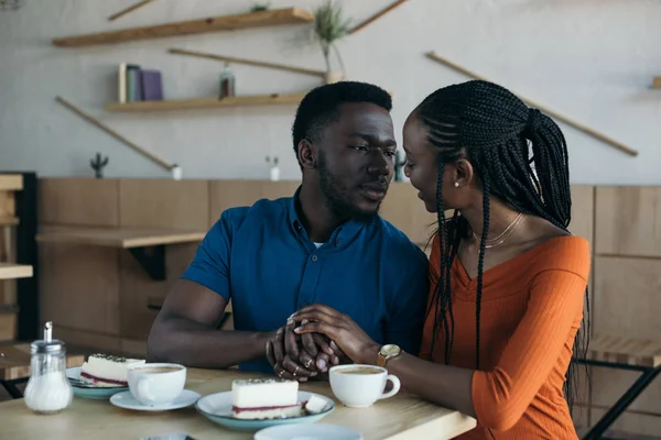 Retrato do casal afro-americano olhando um para o outro e de mãos dadas na data romântica no café — Fotografia de Stock