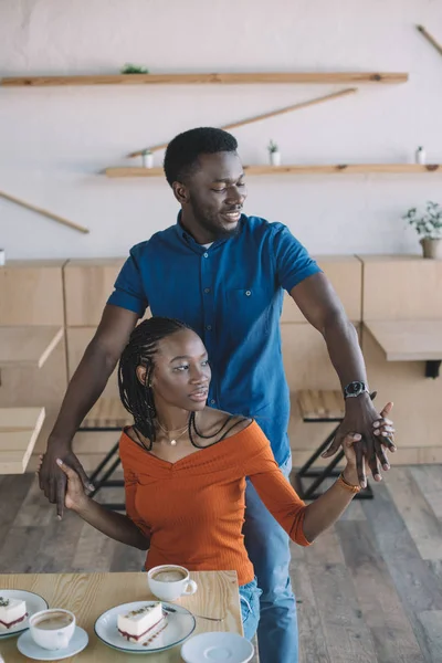 Smiling african american couple holding hands on romantic date in coffee shop — Stock Photo