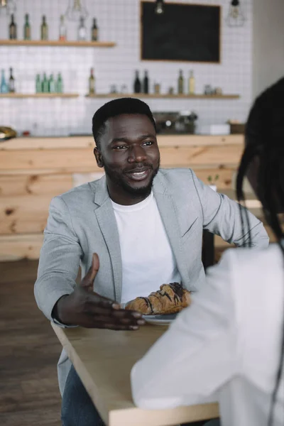 Vista parcial del hombre afroamericano pasar tiempo con un amigo en la cafetería - foto de stock