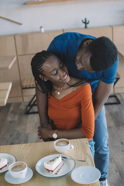 Africano americano uomo abbracciare fidanzata a tavolo in caffè — Foto stock