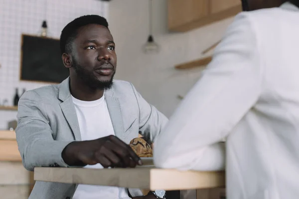 Teilansicht eines afrikanisch-amerikanischen Mannes, der Zeit mit einem Freund im Café verbringt — Stockfoto