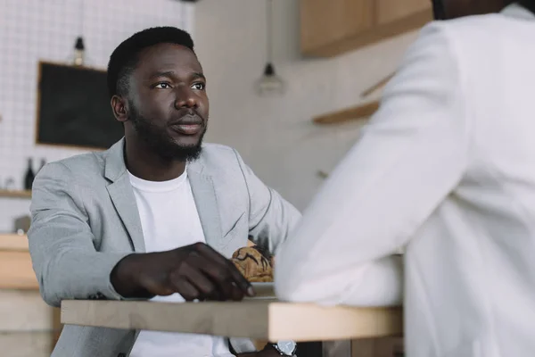 Vista parcial del hombre afroamericano pasar tiempo con un amigo en la cafetería - foto de stock