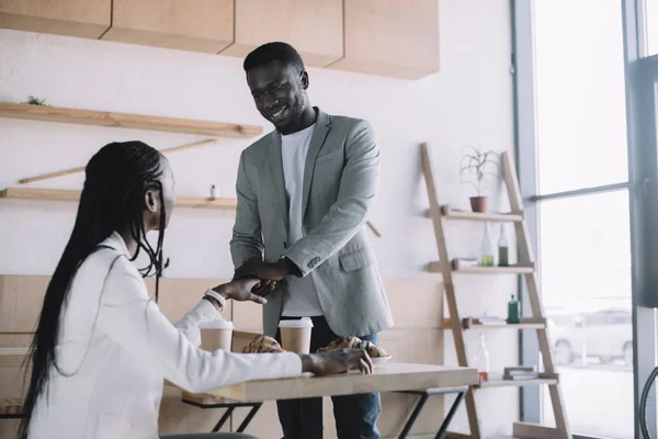 African american friends greeting each other at table in cafe — Stock Photo