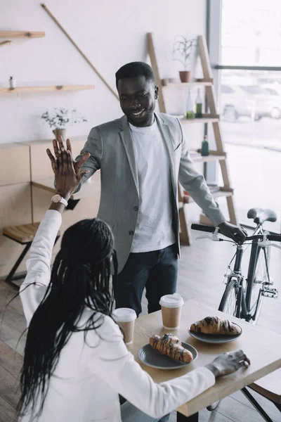 African american friends giving high five to each other at table in cafe — Stock Photo