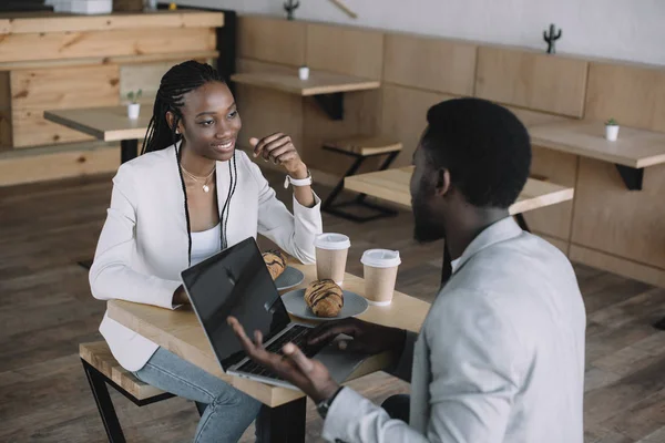 Amigos africanos americanos sentados à mesa com laptop em cafeteria — Fotografia de Stock