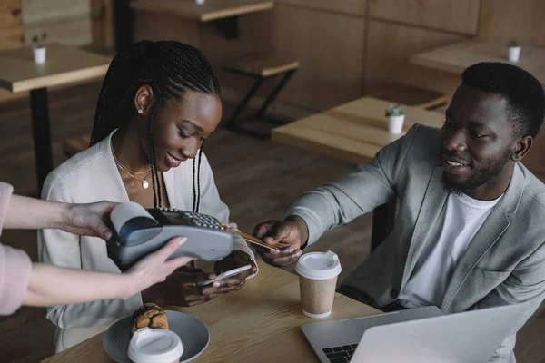African american man paying for order with credit card while spending time with friend in cafe — Stock Photo