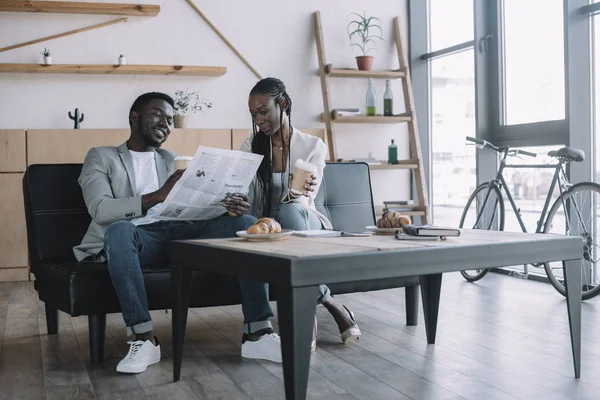 Socios de negocios afroamericanos discutiendo noticias de negocios en cafetería - foto de stock