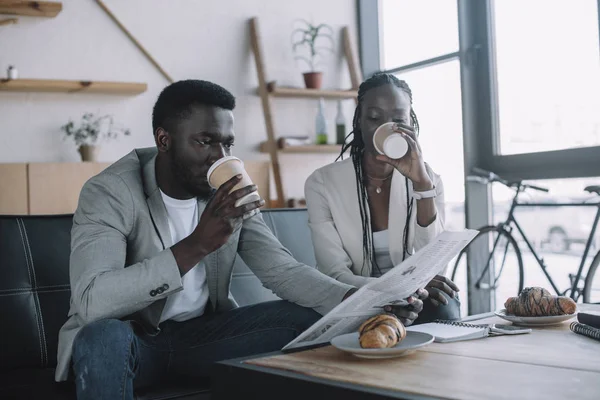 Empresários afro-americanos que bebem café para ir enquanto lêem jornal no café — Fotografia de Stock