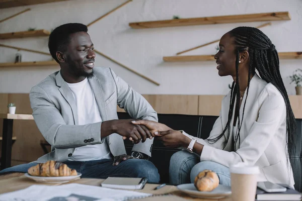 Американские деловые партнеры из Африки пожимают друг другу руки во время деловой встречи в кафе — стоковое фото