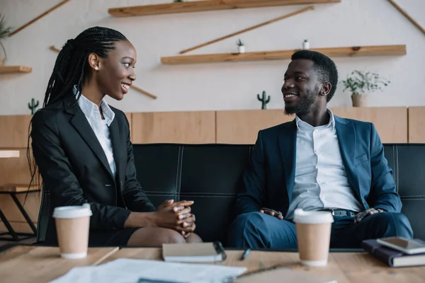 Портрет улыбающихся африканских деловых партнеров, смотрящих друг на друга в кафе — стоковое фото