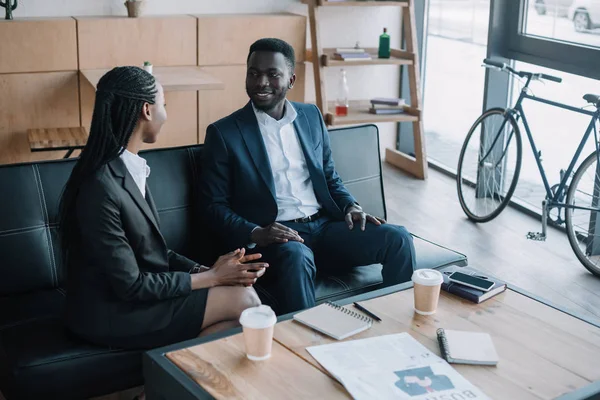 Des partenaires d'affaires afro-américains souriants qui discutent dans un café — Photo de stock