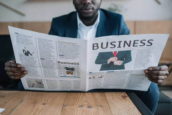 Teilansicht eines afrikanisch-amerikanischen Geschäftsmannes mit Zeitung im Café — Stockfoto