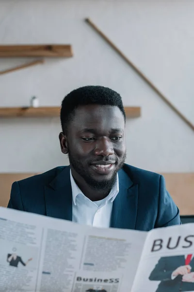 Porträt eines lächelnden afrikanisch-amerikanischen Geschäftsmannes mit Zeitung im Café — Stockfoto