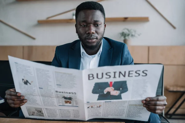 Retrato del hombre de negocios afroamericano leyendo periódico en la cafetería - foto de stock