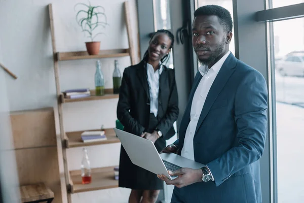 Вибірковий фокус афроамериканського бізнесмена з ноутбуком і усміхненим колегою в кафе — стокове фото