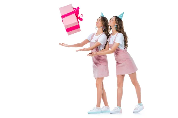 Beautiful young twins catching falling present box isolated on white — Stock Photo