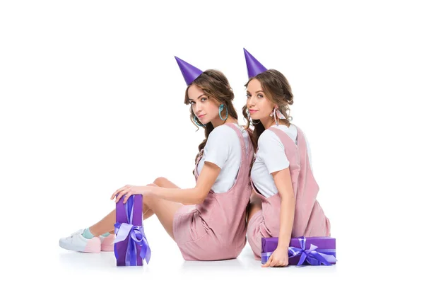 Beautiful young twins in birthday caps looking at camera on white — Stock Photo