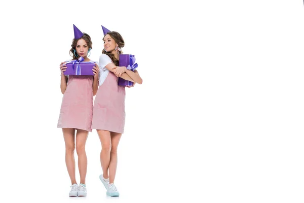 Belle giovani gemelli in cappelli di compleanno azienda presenta isolato su bianco — Foto stock