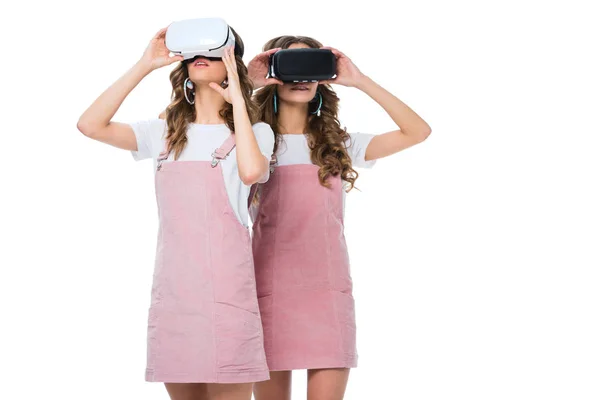 Young twins watching something in virtual reality headsets isolated on white — Stock Photo