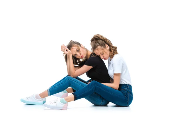 Attractive young twins sitting of floor on white — Stock Photo