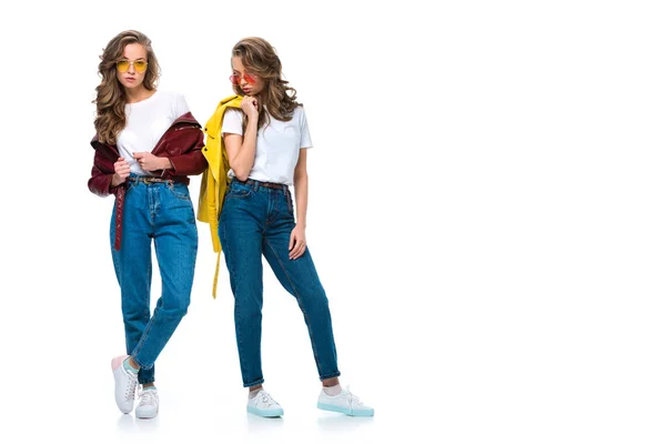 Atractivos gemelos elegantes posando en chaquetas de cuero y gafas de sol aisladas en blanco - foto de stock