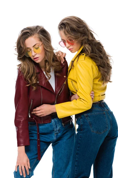 Attractive stylish twins in leather jackets and sunglasses hugging isolated on white — Stock Photo