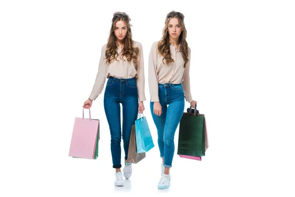 Привабливі молоді близнюки, що ходять з сумками, ізольовані на білому — стокове фото