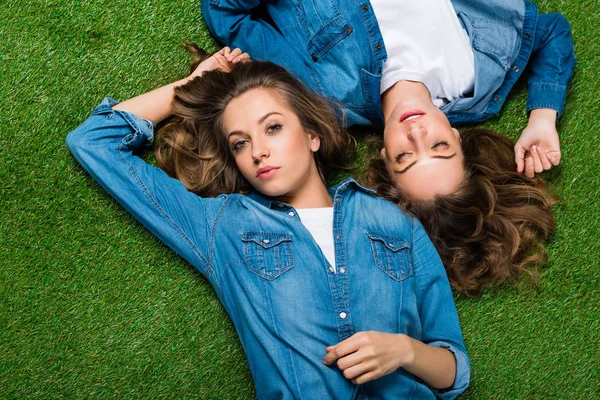 Вид зверху привабливих молодих близнюків, що лежать на зеленій траві — стокове фото