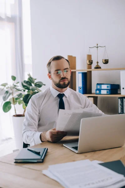 Portrait of lawyer with documents sitting at workplace with laptop in office — Stock Photo