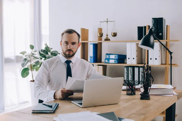 Portrait of lawyer with documents sitting at workplace with laptop in office — Stock Photo